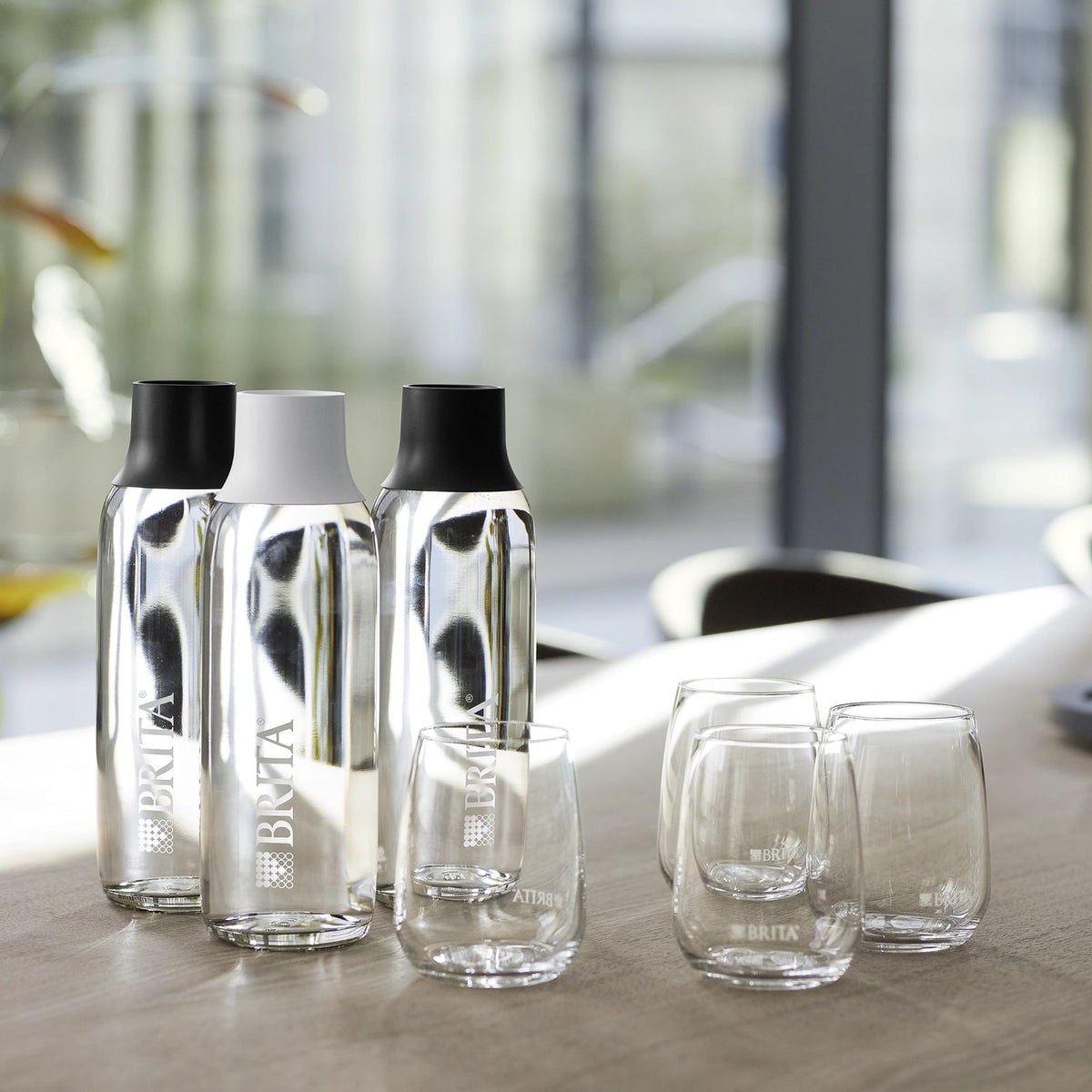 BRITA Wave-flessen en -glazen die op een tafel staan, met een wazige kantoorachtergrond.