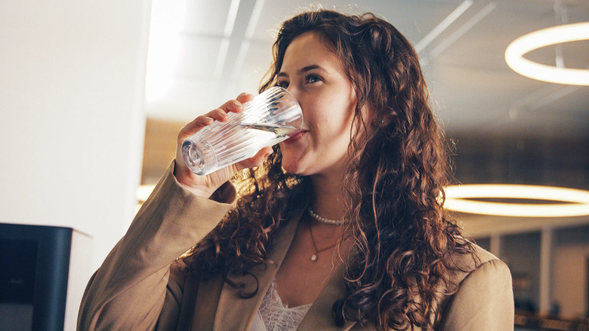 Woman drinking water with a blurred office background