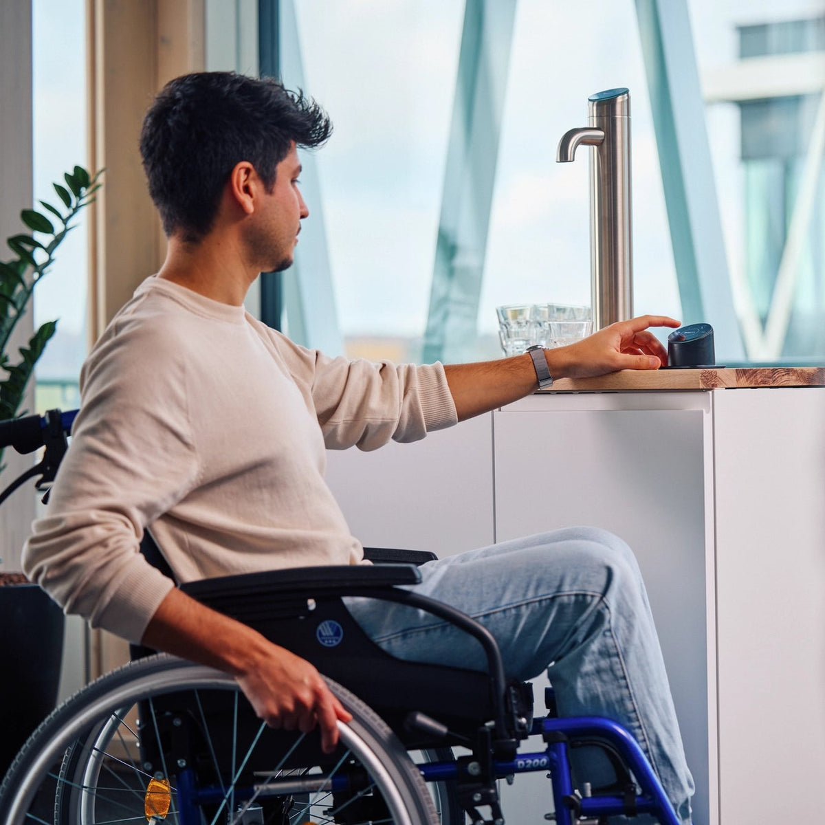 Een man in een rolstoel schenkt water in met behulp van een Easy Access Panel van een BRITA I-Tap.