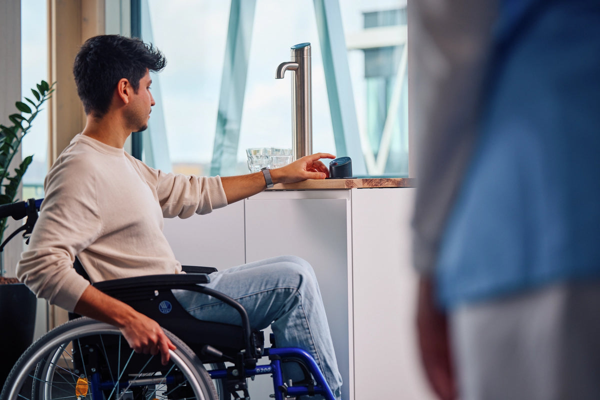 Een persoon in een rolstoel die het Easy Access-paneel bedient in een kantooromgeving 