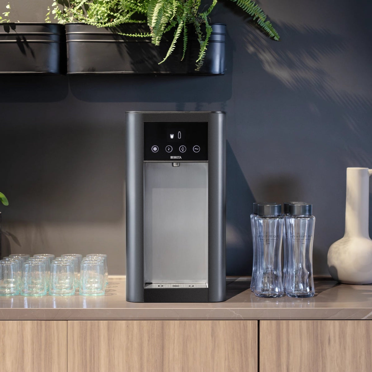 Een Top Pro-waterdispenser op een keukenblad, met glazen en flessen in een moderne keukenomgeving.